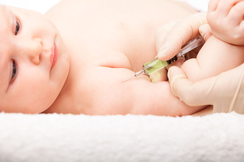 An image of a baby laid down on its back, about to have an immunisation.